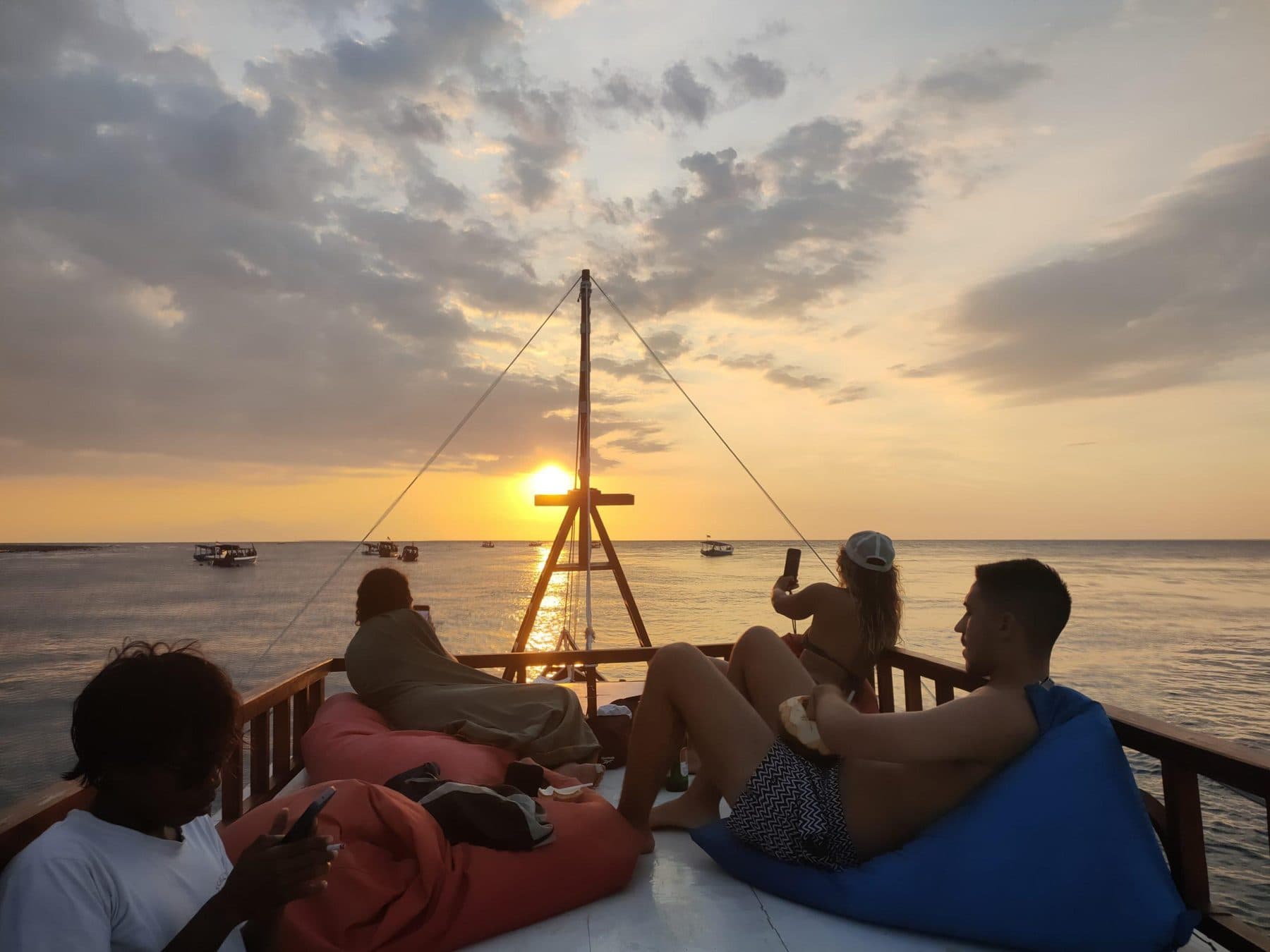 Guests relaxing on a sunset boat deck around the Gili Islands