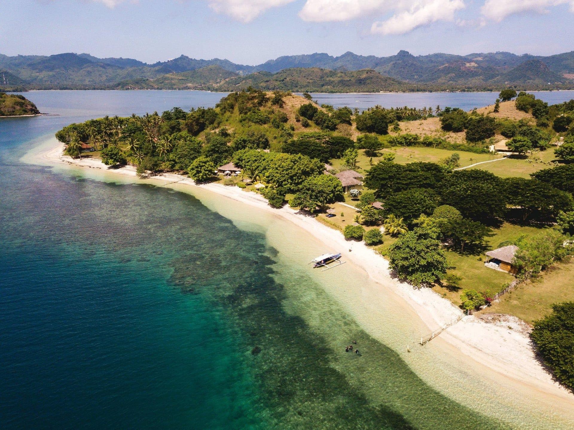 Gili Asahan beach, coral shallows, and a boat on the sand