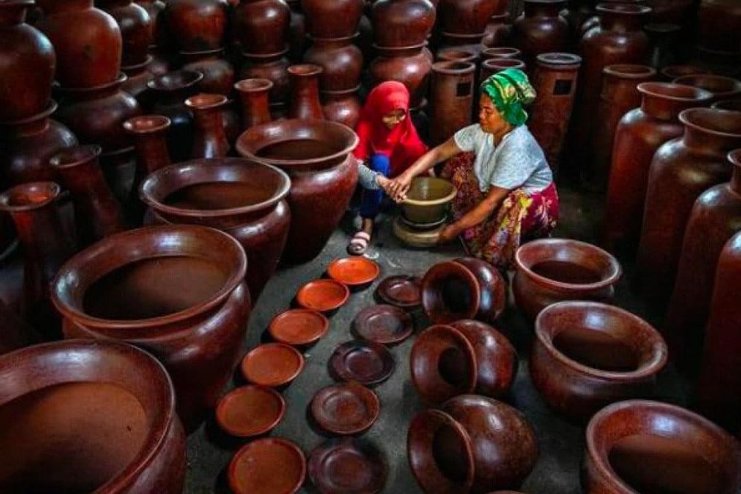 Artisans among rows of handmade clay jars in Banyumulek Pottery Village