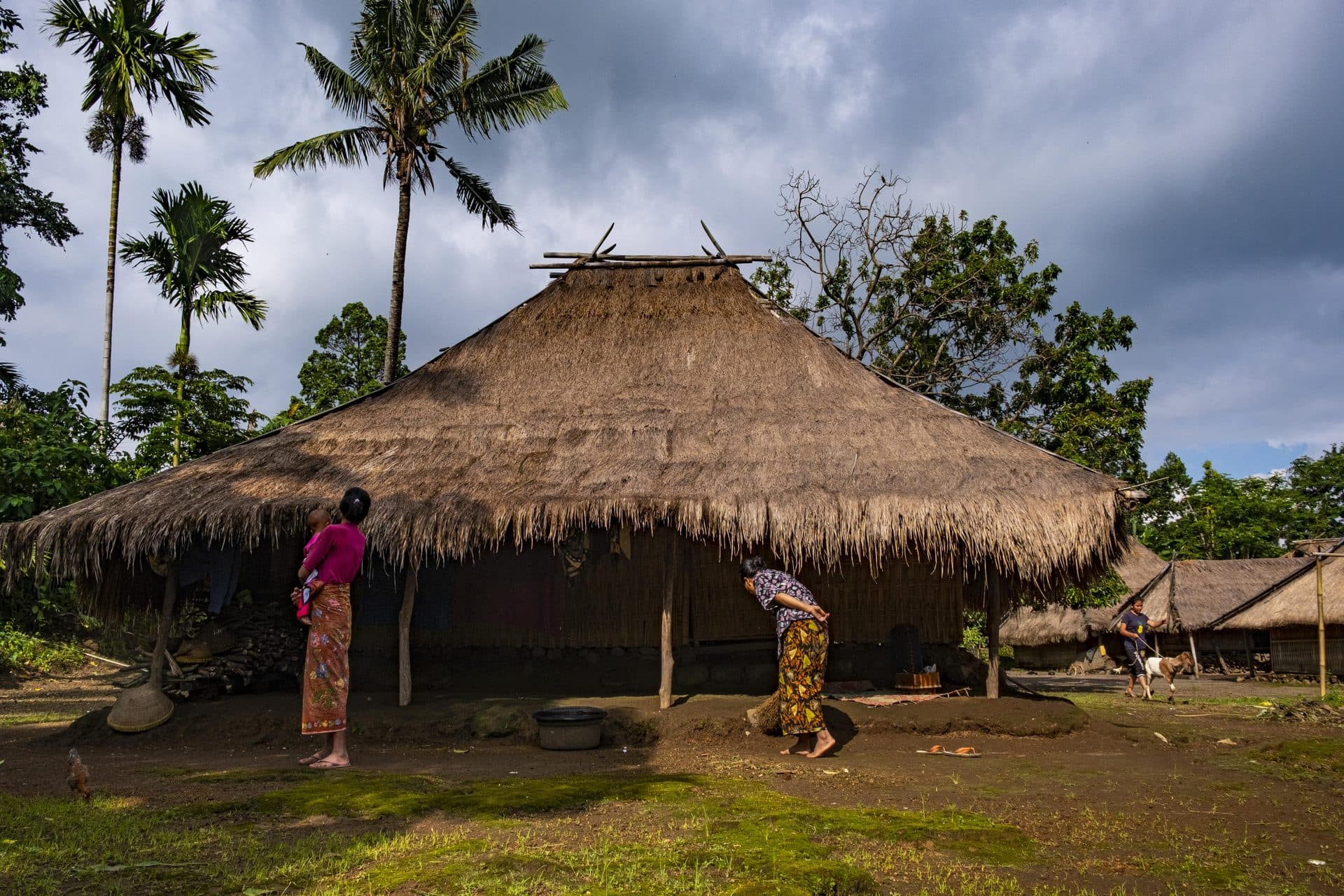 A thatched Sasak house in Senaru Village, with residents in the courtyard