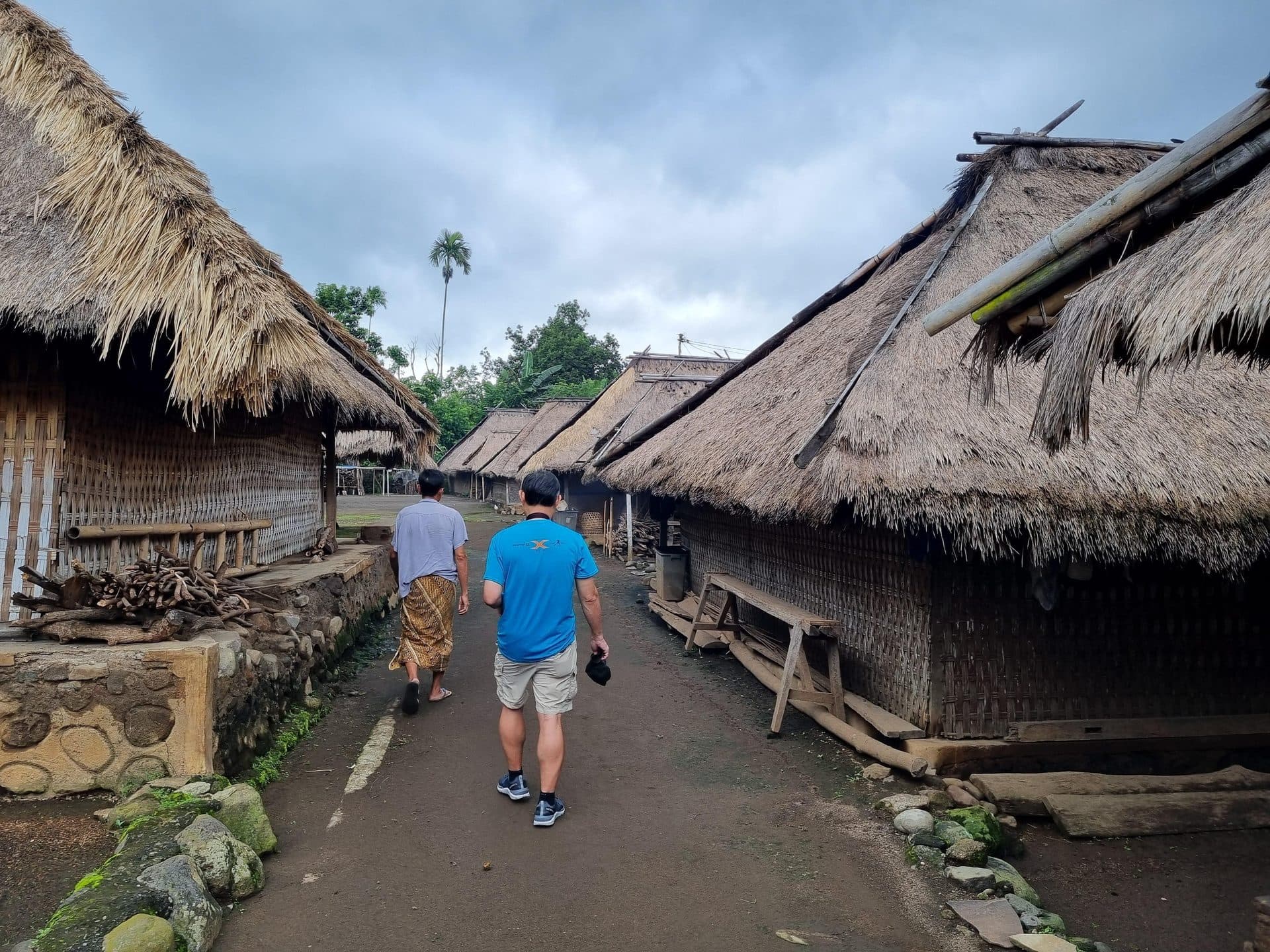 Walking the dirt path between thatched houses in Senaru Village