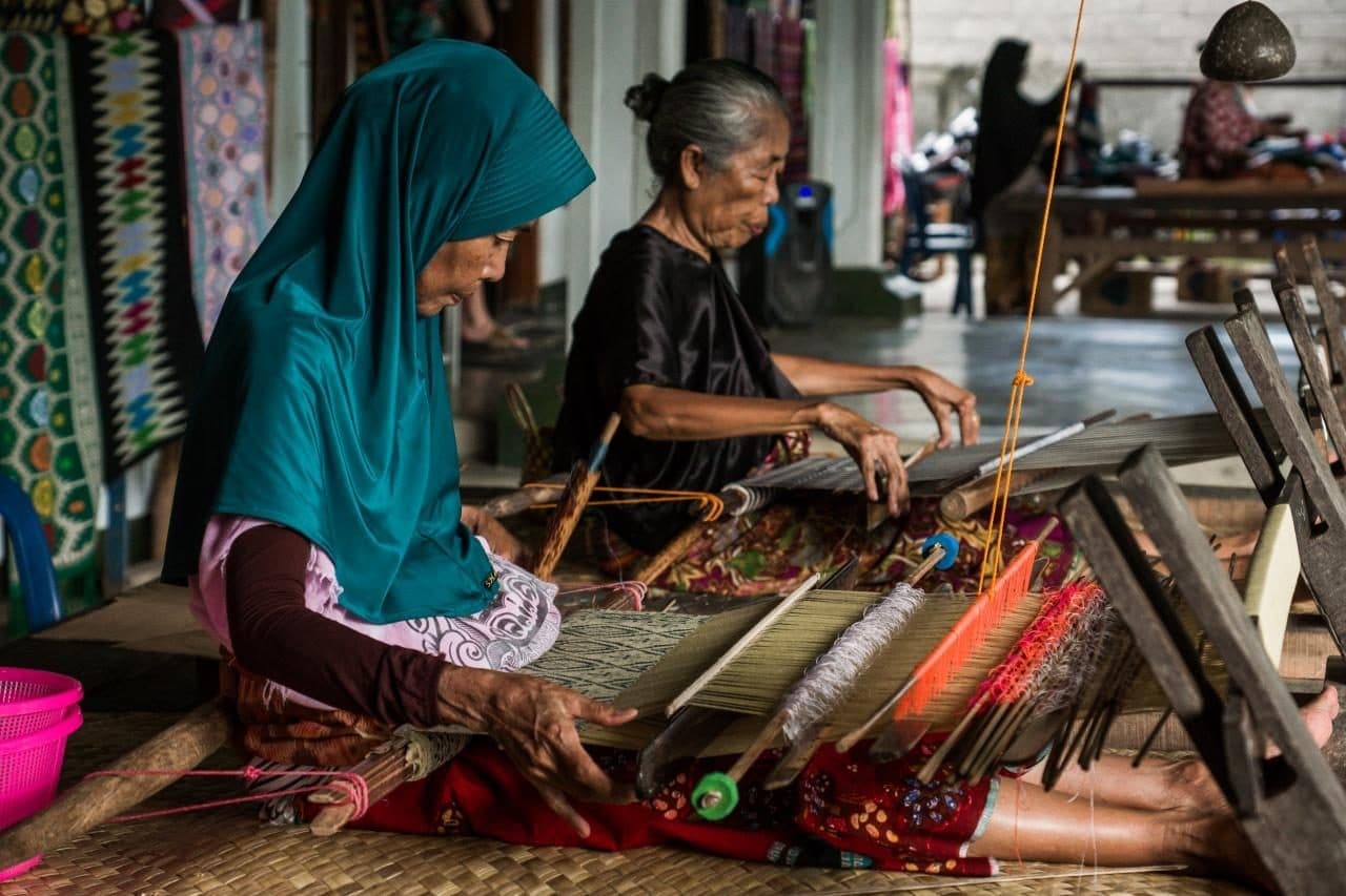 Two women weaving side by side on traditional looms in Sukarara