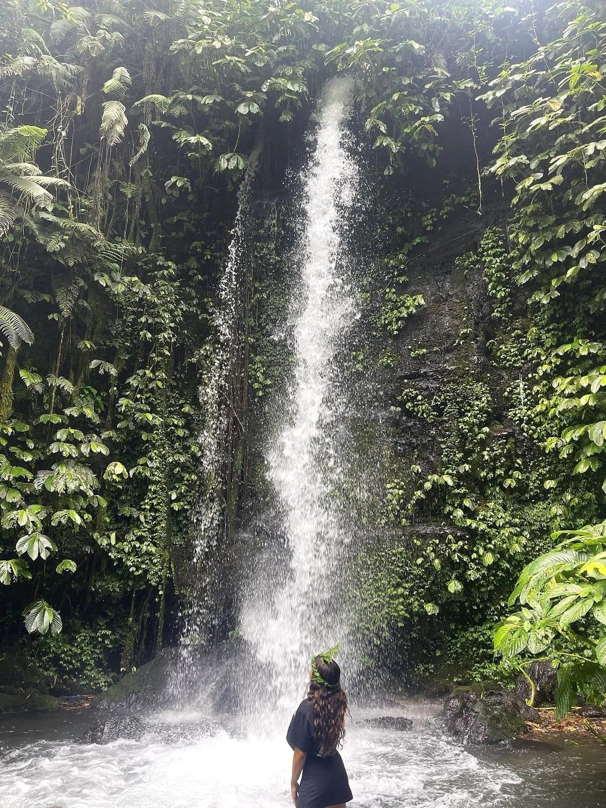 A visitor at a jungle waterfall in the countryside around Tetebatu