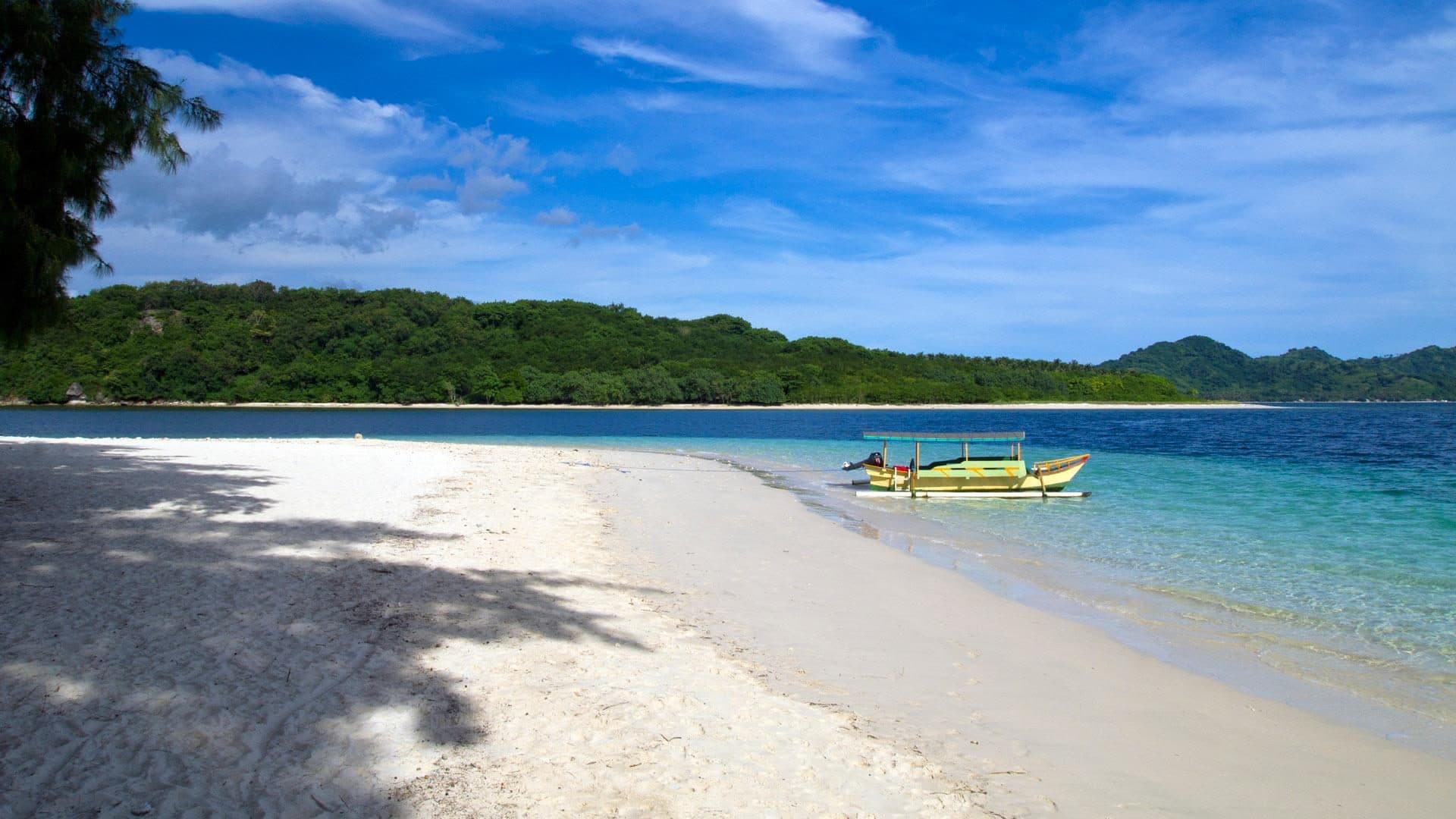 Quiet white-sand beach and a boat at Gili Nanggu