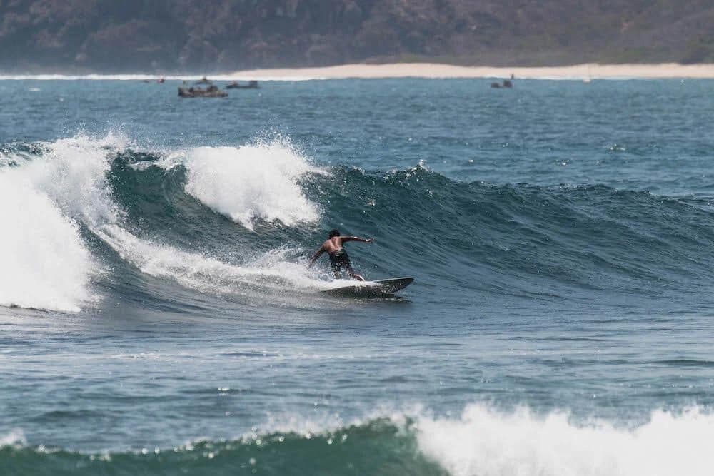 Surfer riding a wave at Mawi Beach