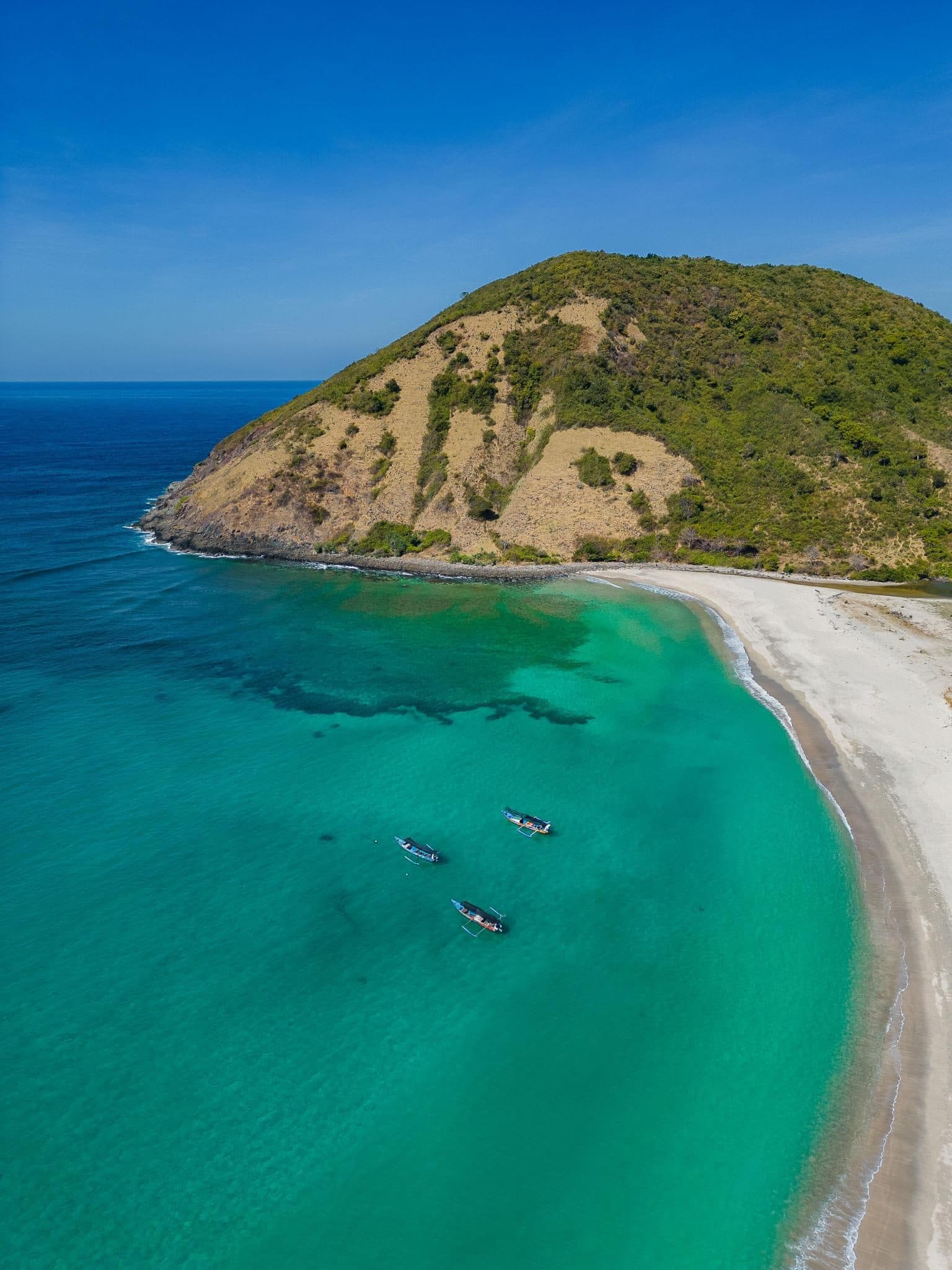 Boats in clear water below the hill at Mawun Beach