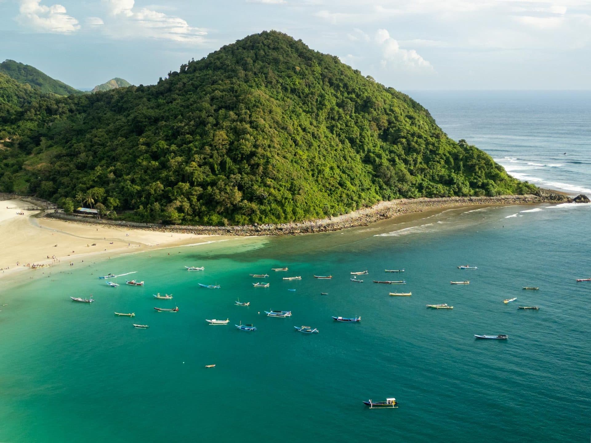 Green headland and fishing boats at Selong Belanak