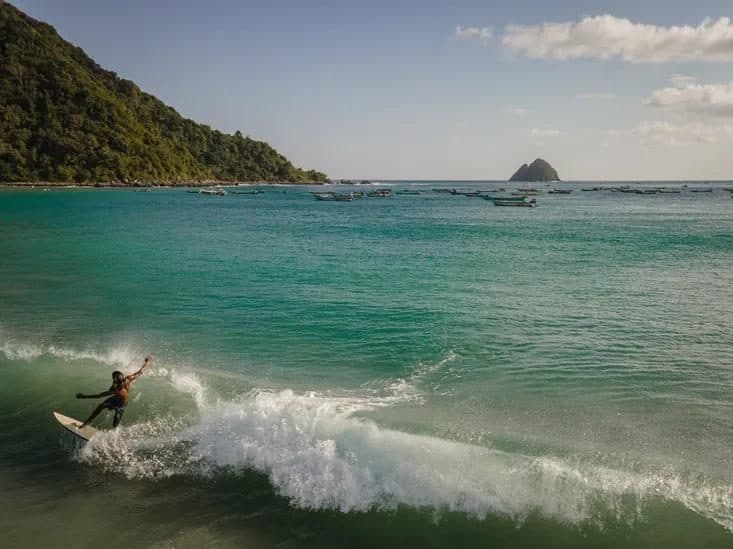 Surfer at Selong Belanak with the bay behind