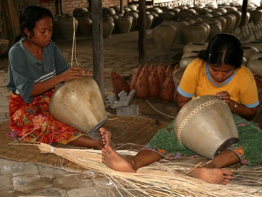 Artisans finishing pottery with rattan bindings in Banyumulek