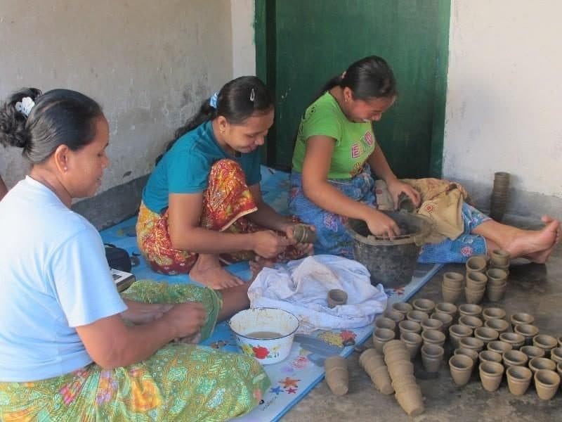 Women shaping small clay cups by hand in Banyumulek