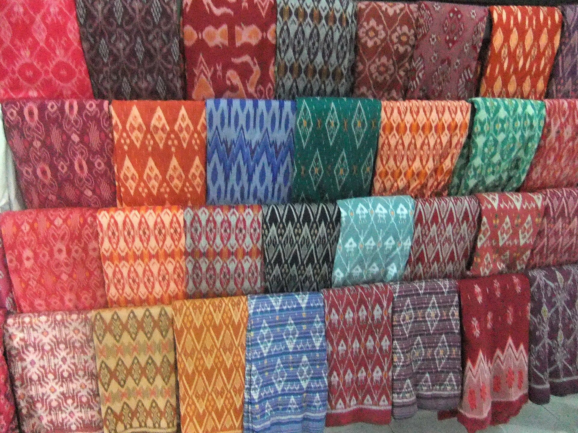 Rows of colorful Lombok ikat textiles hanging in a workshop