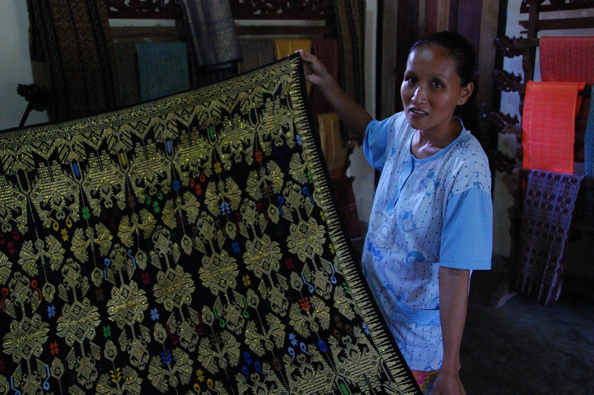 A weaver presenting a gold-patterned Sasak songket textile