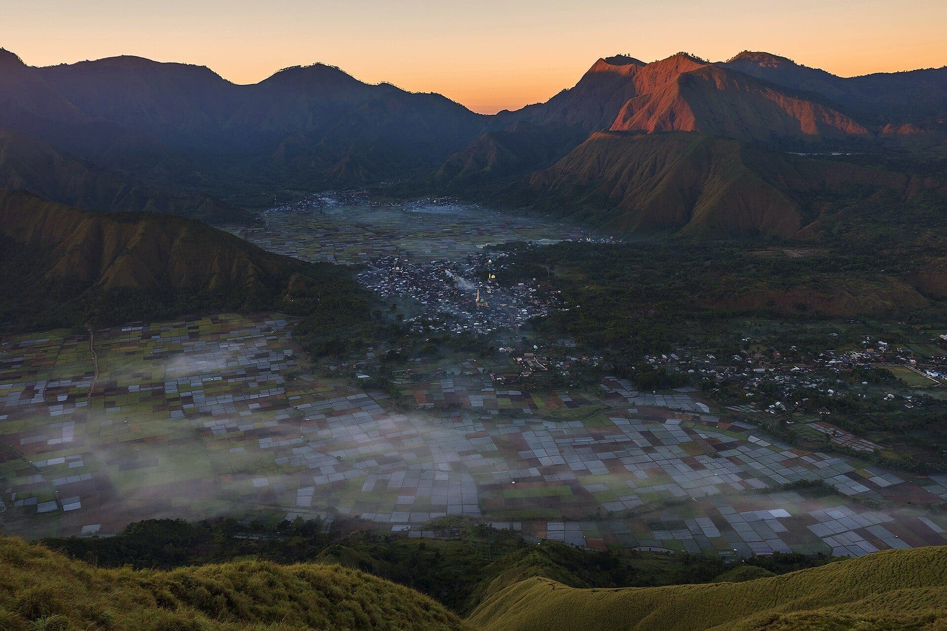 Sunrise over Sembalun Valley, with patchwork fields beneath the hills