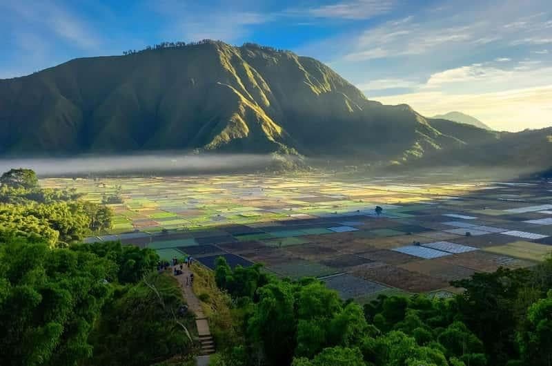 A hillside viewpoint looking across misty Sembalun Valley