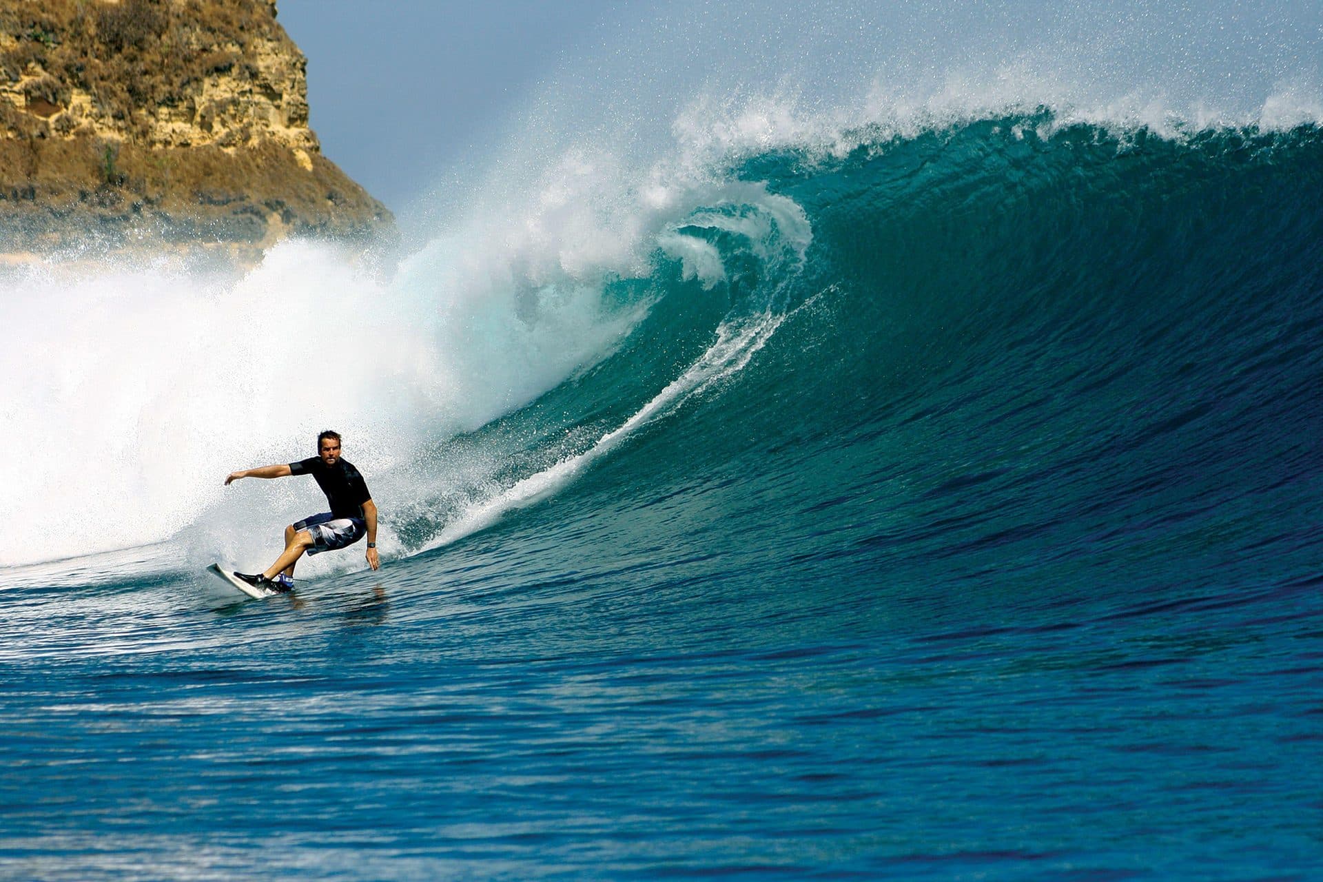 A surfer riding a powerful barreling wave at Mawi Beach