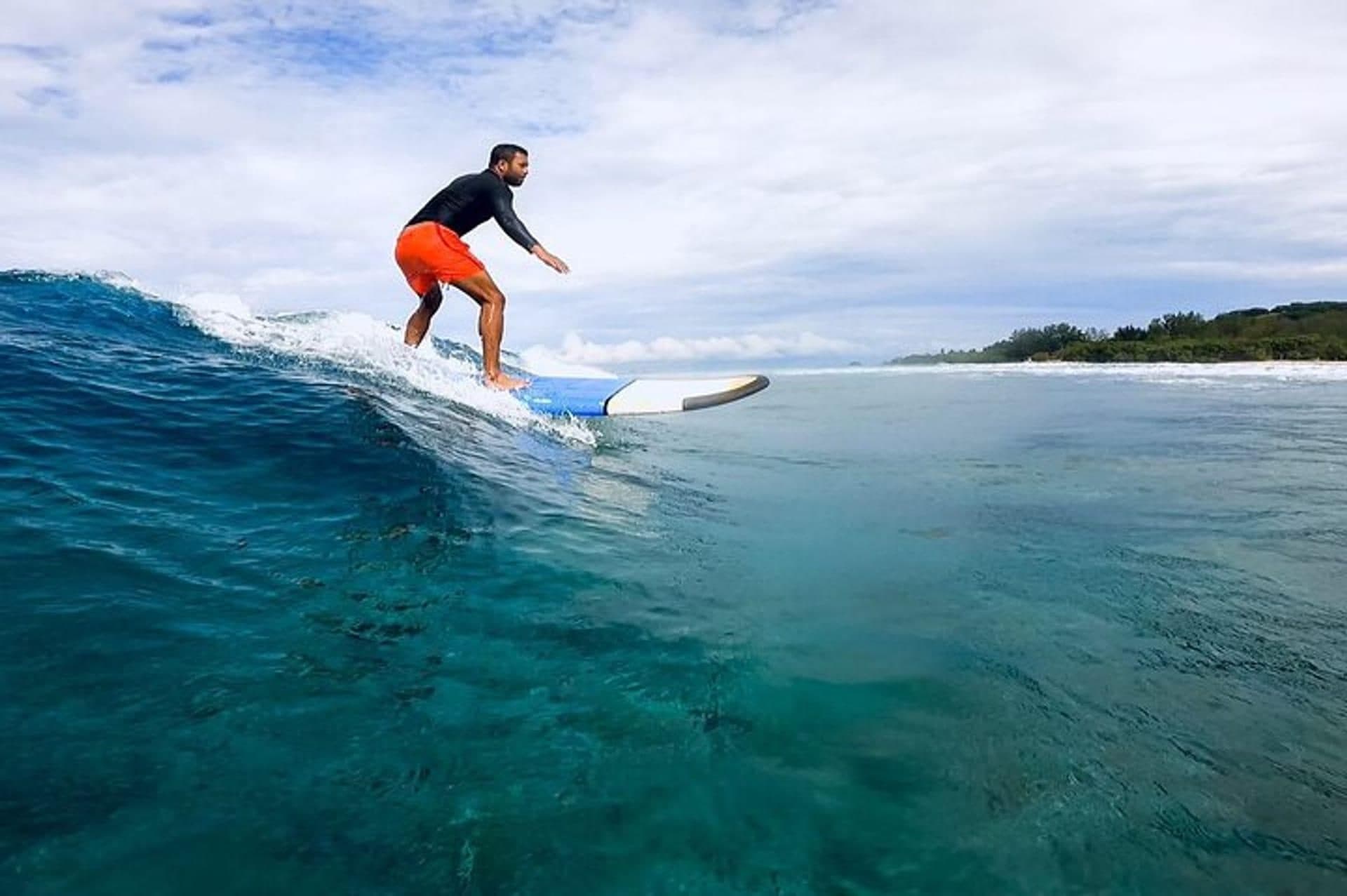 A surfer riding a turquoise wave off Lombok